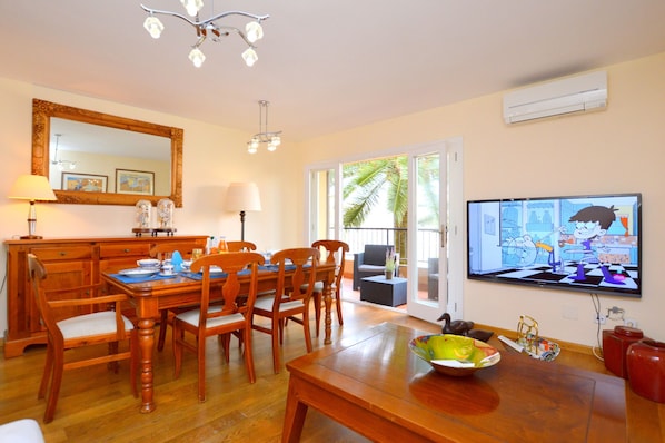 Un comedor con una mesa y sillas de madera, un espejo grande y un televisor que muestra una caricatura.
