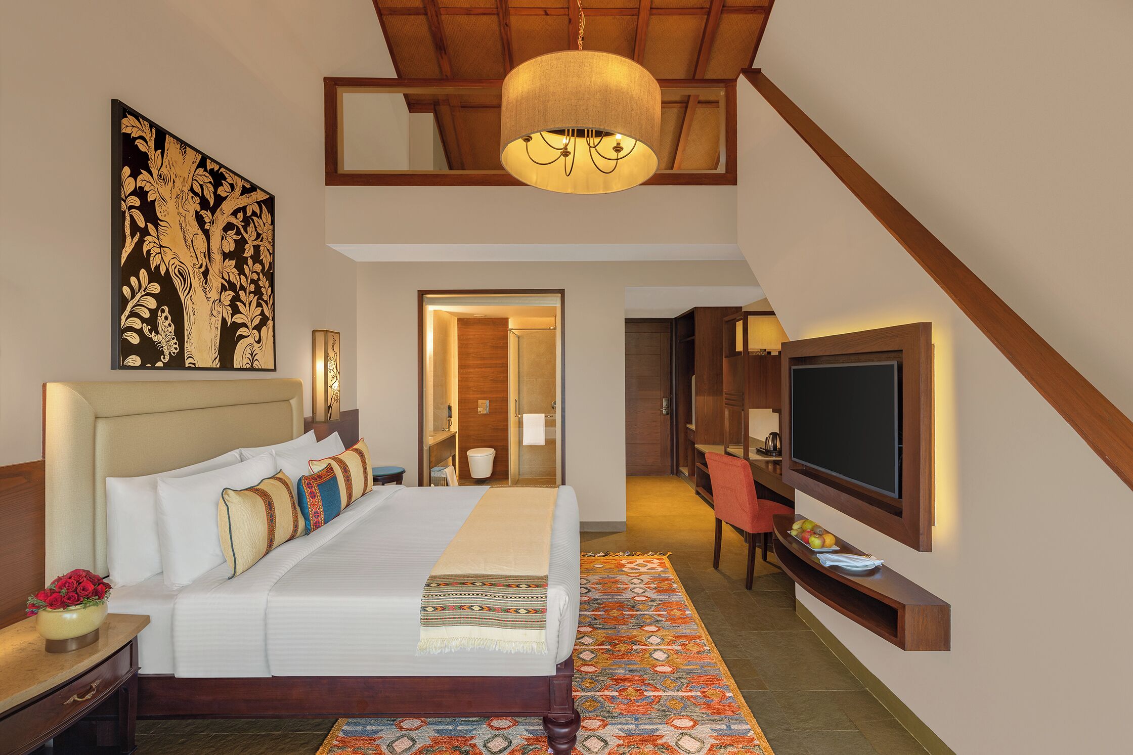A hotel room with a large bed, a television, a desk, and a chair.