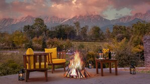 Una fogata con sillas y una mesa dispuesta al aire libre, con vistas a un paisaje montañoso.