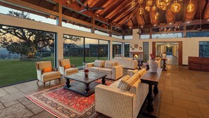 Un espacio interior amplio con ventanas grandes, un techo alto con vigas de madera y varias opciones de asientos.