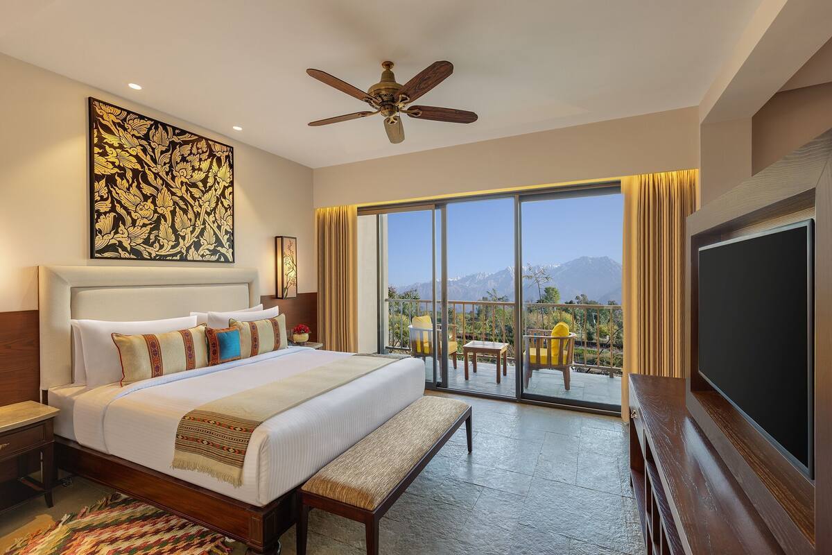 Quarto de hotel com cama, ventilador de teto, janela grande com vista e televisão de tela plana.