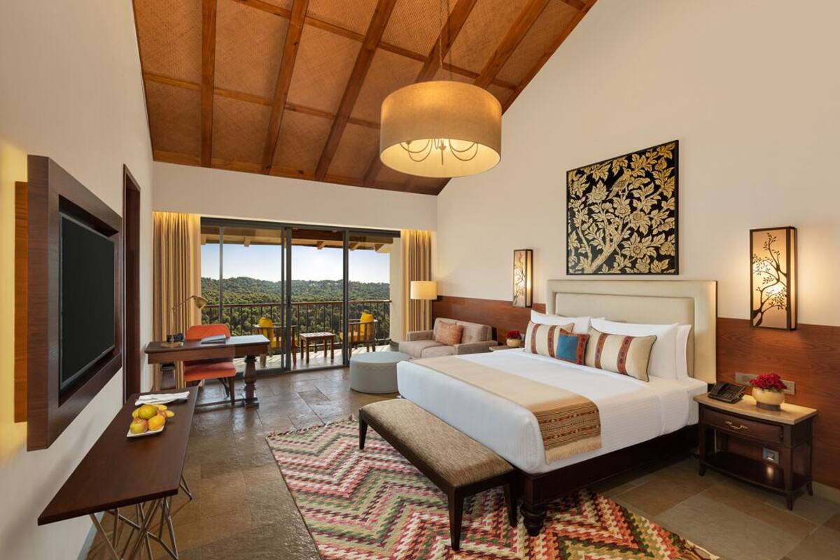 Um quarto espaçoso com uma cama grande, uma escrivaninha, uma cadeira e uma varanda com vista.