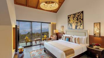 A spacious bedroom with a large bed, a balcony with a view of mountains, and a chandelier.