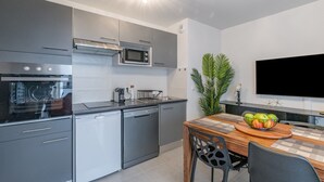 A modern kitchen with grey cabinets, a microwave, a dishwasher, and a dining area with a wooden table and chairs.