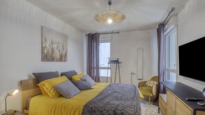 A bedroom with a bed, bedside table, lamp, and a TV.