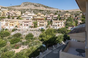 A residential area with multi-story buildings, a rocky hillside, and a clear sky.