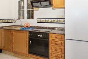 A kitchen with wooden cabinets, a stove, a sink, and a refrigerator.