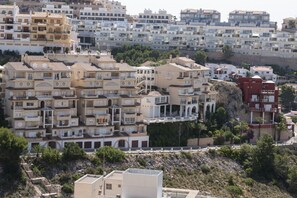 A densely packed residential area with multi-story buildings, balconies, and a rocky hillside.
