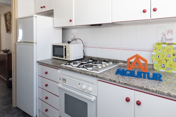 A kitchen with white cabinets, a microwave, a gas stove, and an oven. - EL RACO, B-8º-15 (Cullera)
