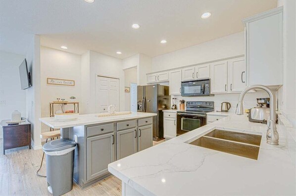 A modern kitchen with white cabinetry, a central island, and built-in appliances.