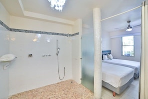 Enjoy a comfortable stay in this well-appointed room featuring a bed, shower with glass door, and ceiling fan for ventilation.