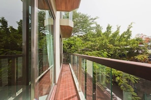 Enjoy the serene view of lush greenery from this balcony with a tiled floor and a decorative accent above the railing.