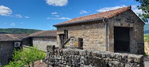 A stone building with a tiled roof, a small door, and a stone wall.