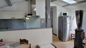 A compact kitchen with a refrigerator, microwave, and a small dining area with a table and chairs. - Gîte clim garage, Les Vans Ardèche, large panoramic terrace, gorges Ardèche (Les Assions)