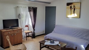 A room with a bed, a TV, a wooden cabinet, a chair, and a table with a bowl. - Gîte clim garage, Les Vans Ardèche, large panoramic terrace, gorges Ardèche (Les Assions)