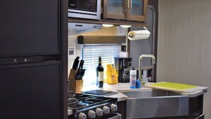Une cuisine de taille réduite équipée d’une cuisinière, d’un four, d’un four à micro-ondes et d’un évier.