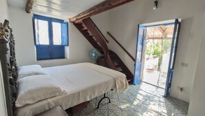 Une chambre à coucher avec un lit, une fenêtre, un ventilateur et un escalier.
