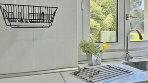 Une cuisine moderne dotée d’un évier encastré, d’une fenêtre donnant sur un espace verdoyant et d’un porte-ustensiles.