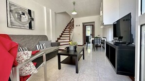 Un salon moderne avec un canapé, une table basse et un escalier menant à une autre pièce.