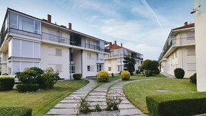 Een rij moderne appartementencomplexen met twee verdiepingen, balkons, een pad van natuursteen en verzorgde gazons.