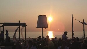 Een strandsetting met mensen die ontspannen onder parasols en een podium.