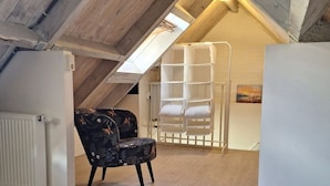 Slaapkamer met kap, een radiator, een stoel, een bed en een witte inloopkast.
