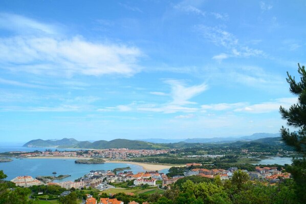 A coastal town with a beach, buildings, and hills in the background.