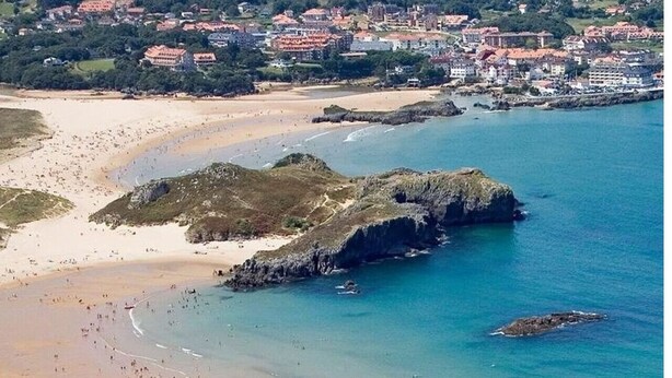 Une ville côtière avec une plage, des affleurements rocheux et des bâtiments en arrière-plan.