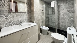 Un baño moderno con baldosas estampadas, un espejo grande, un bidé y un inodoro.
