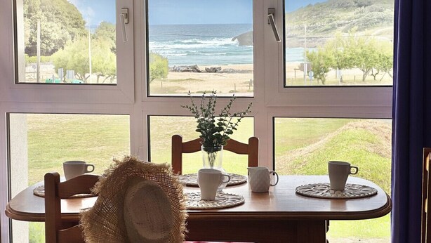 A dining table with a view of the ocean through large windows. - Apto en primera línea - La Arena 4107 (Arnuero)