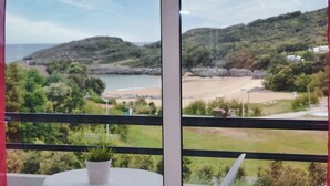 Un balcón con vista a una playa y colinas.