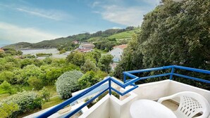 A balcony with a table and chairs, overlooking a scenic landscape with hills and a body of water. - Apartamento con vistas - La Arena 4612 (Isla)