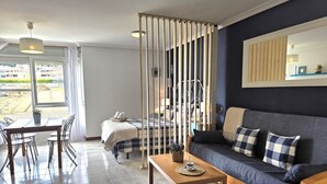 A modern living room with a sofa, a dining table, and a bed. - Loft en Isla Playa - El Corrillo 5604 (Arnuero)