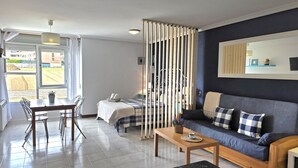 A modern living room with a sofa, a dining table, and a bed. - Loft en Isla Playa - El Corrillo 5604 (Arnuero)