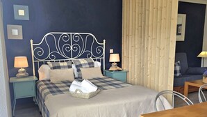 A bedroom with a bed, two bedside tables, a wooden headboard, a nightstand, a chair, and a table. - Loft en Isla Playa - El Corrillo 5604 (Arnuero)