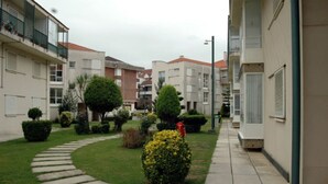 A residential area with a pathway, neatly trimmed hedges, and a small garden. - Loft en Isla Playa - El Corrillo 5604 (Arnuero)