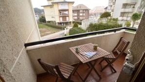 A balcony with a table and chairs, a security camera, and a view of surrounding buildings.