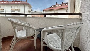 Un balcón con dos sillones de mimbre y una mesita.