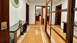 Un pasillo con una puerta de madera, un espejo y un sofá rojo al fondo.