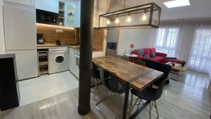 Eine moderne Küche mit Essbereich, einer Waschmaschine und einem roten Sofa im Wohnzimmer.