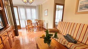 A living room with a sofa, a coffee table with a vase, and a dining area with chairs and a table. - Apartamento en Ris con garaje - Pineda 6405 (Noja)