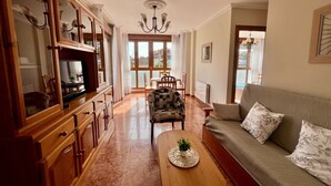 A spacious living room with a sofa, armchair, and wooden cabinet. - Apartamento en Ris con garaje - Pineda 6405 (Noja)