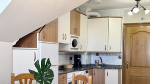 A compact kitchen with white and wooden cabinets, a coffee maker, and a sink. - Apartment close to Ris Beach - Pineda 6606 (Noja)