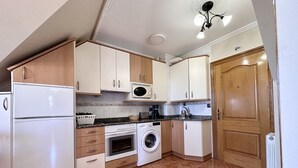 A compact kitchen with a refrigerator, oven, microwave, and washing machine. - Apartment close to Ris Beach - Pineda 6606 (Noja)