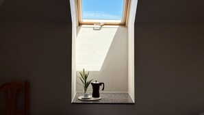 A skylight with a potted plant and a black kettle on a small table. - Apartamento en playa de Ris - Pineda 6607 (Noja)