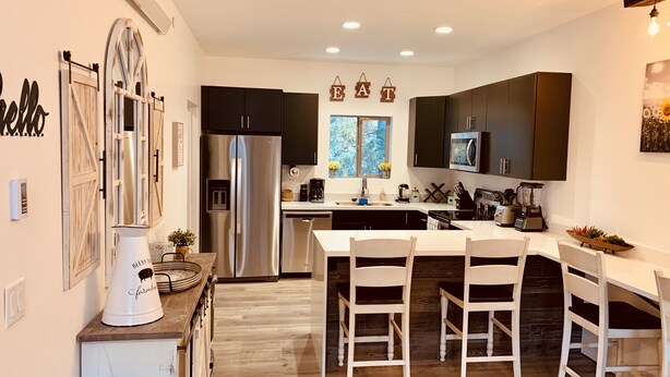 A modern kitchen with a central island, stainless steel appliances, and dark cabinetry.