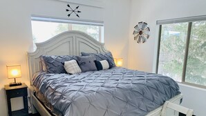 A bedroom with a bed, bedside lamps, a chair, and a decorative wall clock.