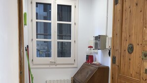 Ein Korridor mit einem gemusterten Boden, einem Heizkörper, einem Holzschrank, einer Tür und einem Fenster mit Blick auf Gebäude.