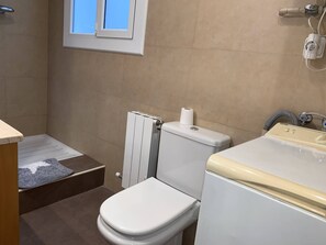 A bathroom with a toilet, a radiator, a window, and a sink. - Renovated apartment across from Casa de les Punxes (Barcelona)