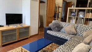 Ein Wohnzimmer mit einer Couch, einem Couchtisch, einem Fernseher und einem Bücherregal.